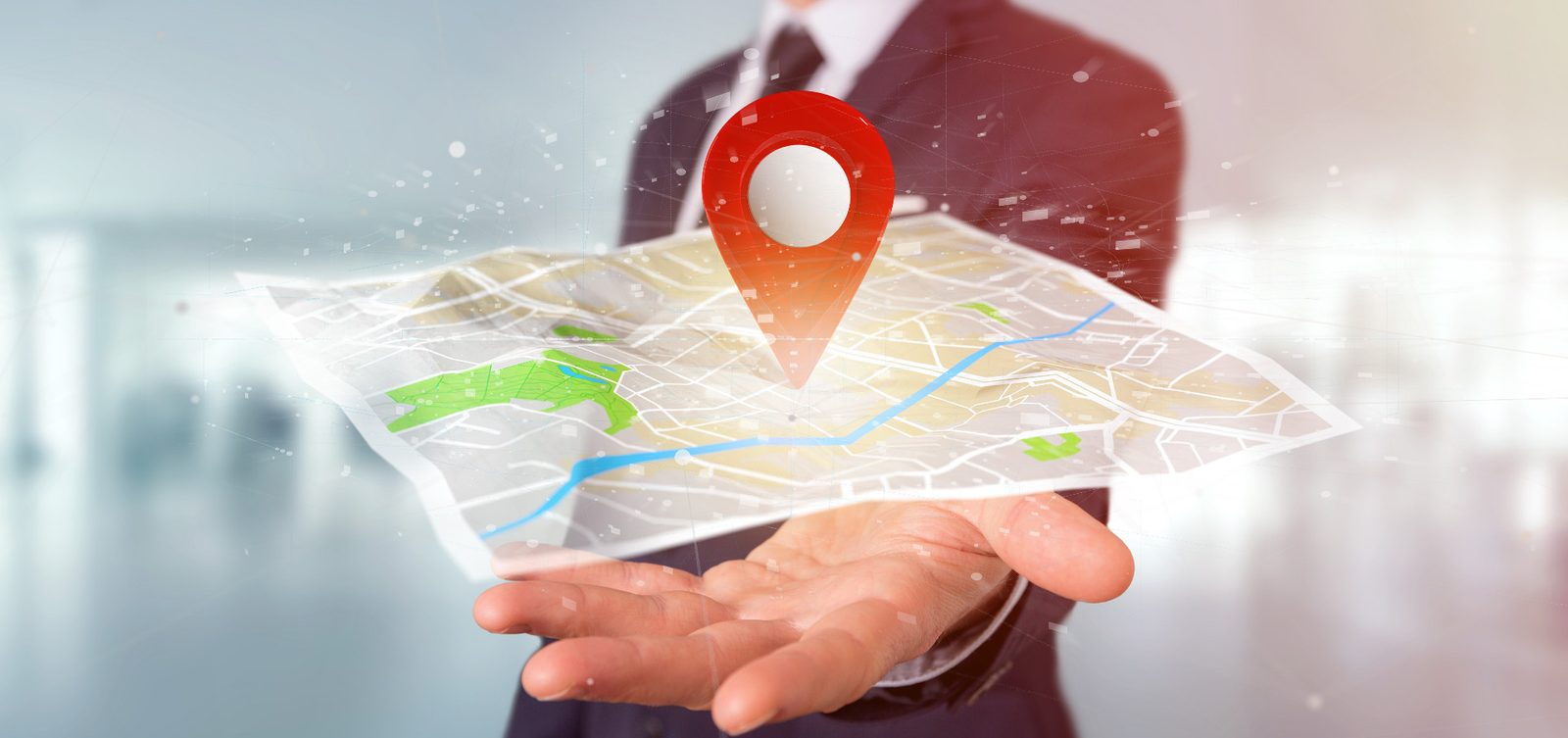 A hand holding a map with a location pin marker
