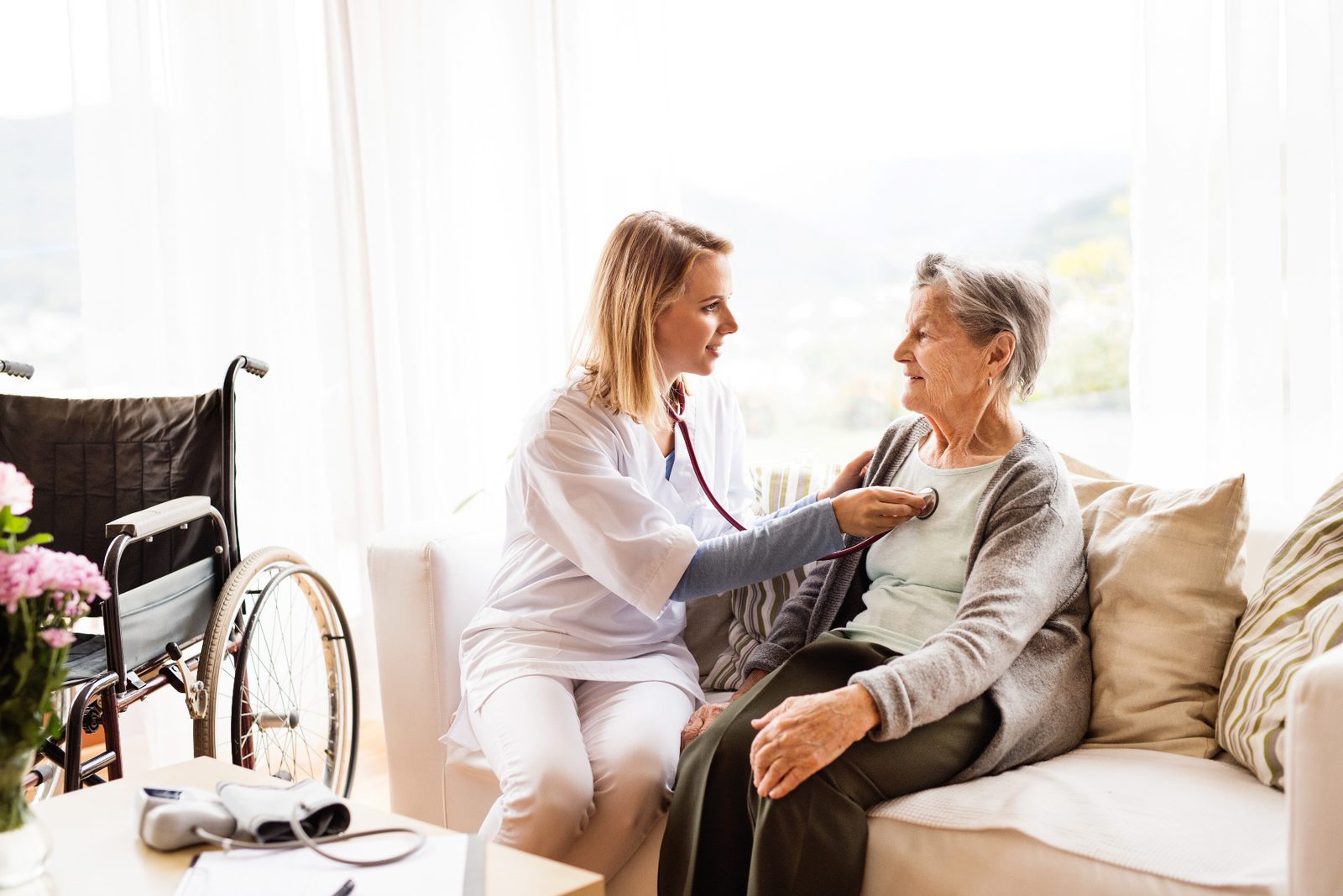 A health visitor checking an older woman's blood pressure at home