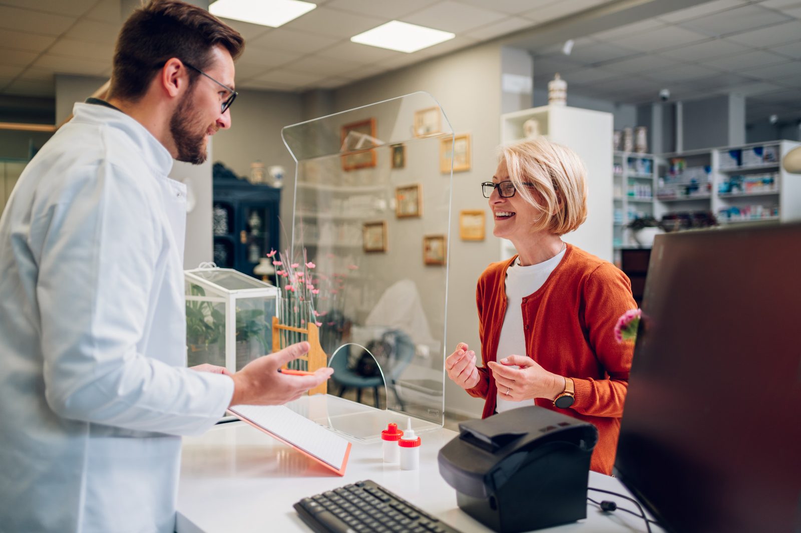 A pharmacist assisting an older woman at the pharmacy counter