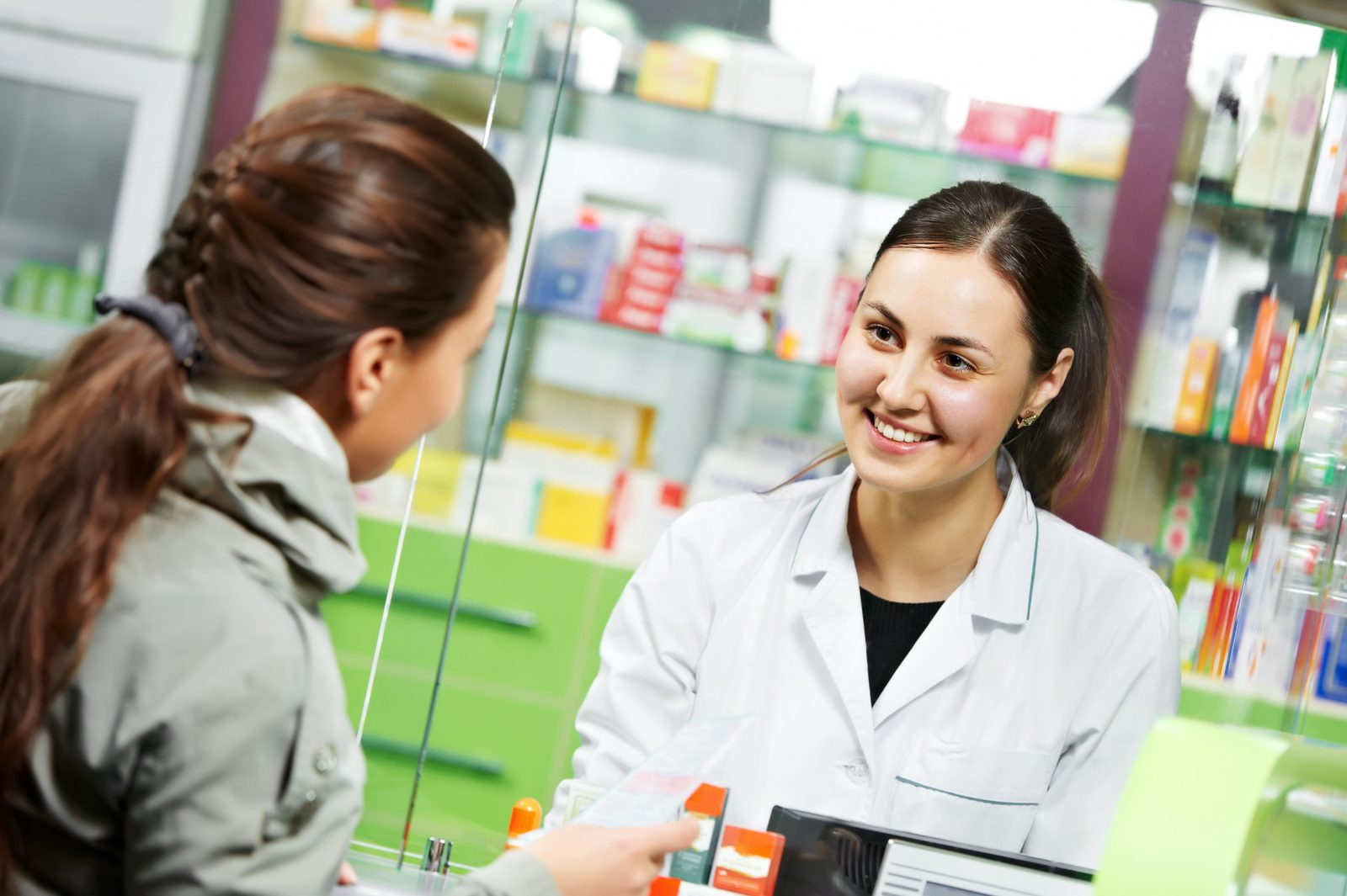 A pharmacist serving customers at the pharmacy counter
