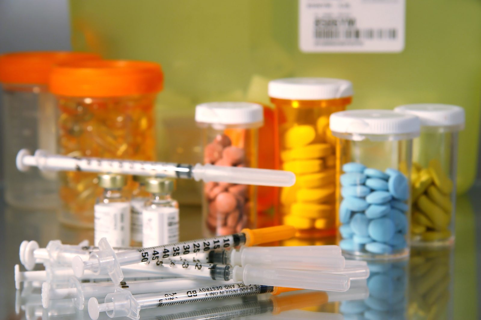 Prescription bottles, syringes and tablets on a counter