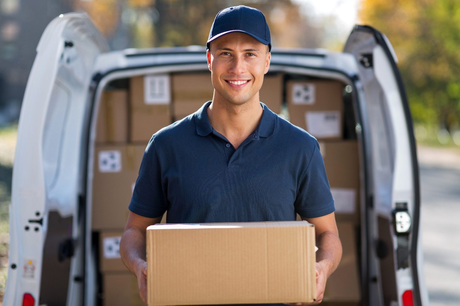 A delivery driver holding a parcel at the back of a van