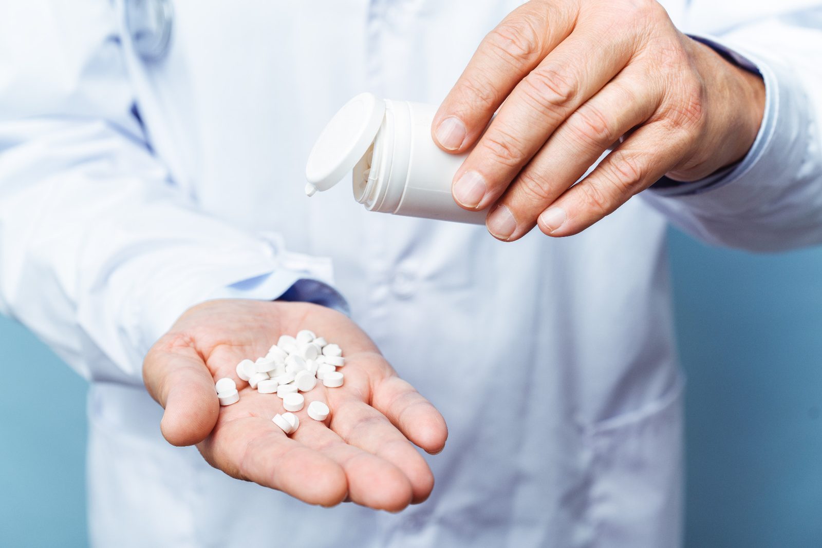 White tablets poured from a bottle into an open hand